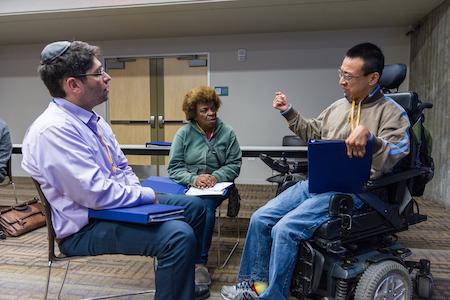 Three people deep in dialogue, 一个 geturing with his hand.